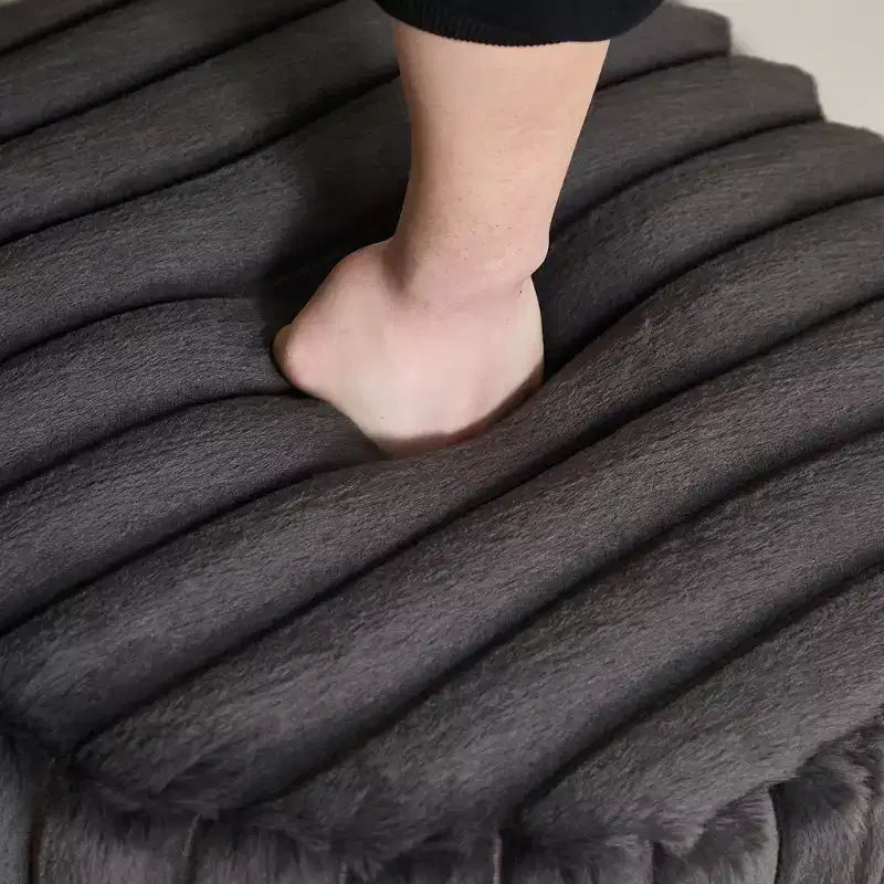 Repose-pieds moelleux et volumineux avec pieds en métal et fausse fourrure.